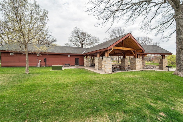 back of house with a lawn, a fireplace, a patio area, a gazebo, and a shingled roof