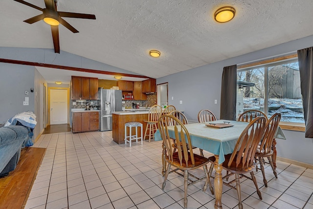 dining room with a textured ceiling, light tile patterned floors, ceiling fan, baseboards, and lofted ceiling