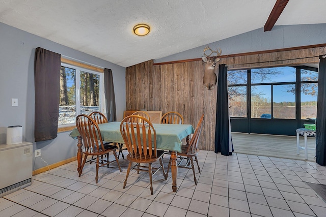 dining space with vaulted ceiling, wooden walls, a textured ceiling, and light tile patterned floors