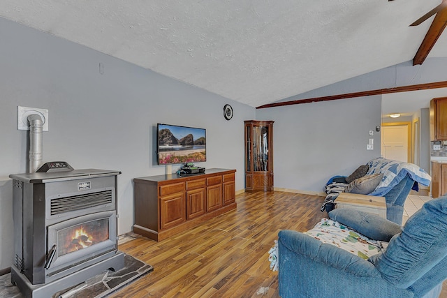 living area featuring a textured ceiling, light wood-type flooring, lofted ceiling, a ceiling fan, and a wood stove