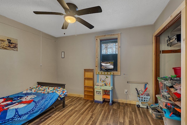 bedroom featuring baseboards, wood finished floors, a textured ceiling, and ceiling fan