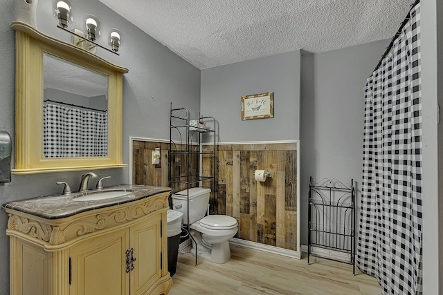 bathroom with vanity, toilet, wood finished floors, and a textured ceiling