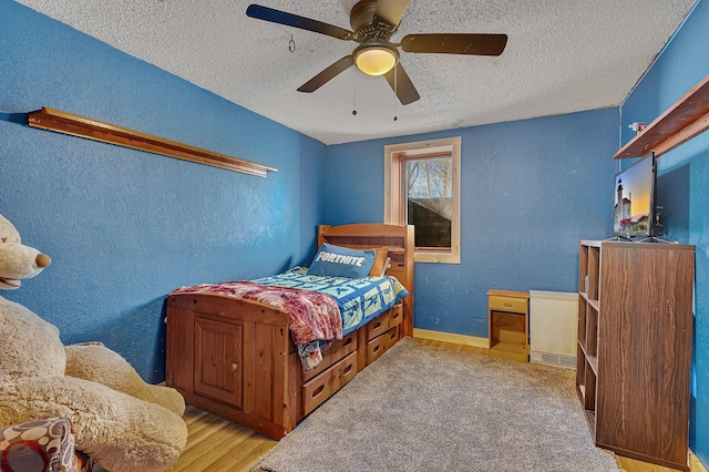 bedroom featuring a textured wall, a textured ceiling, and wood finished floors
