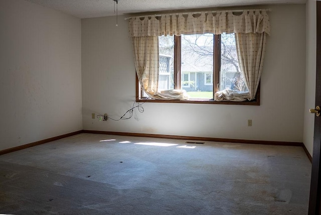 spare room with visible vents, baseboards, carpet, and a textured ceiling