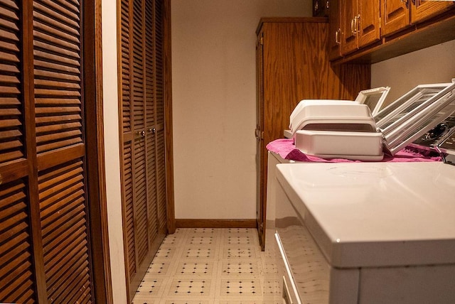 washroom with light floors, baseboards, cabinet space, and washer and clothes dryer