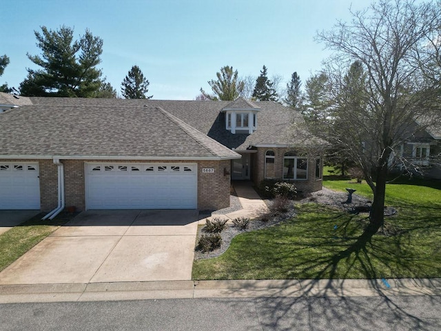 view of front of property with a shingled roof, a front lawn, concrete driveway, an attached garage, and brick siding