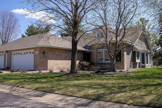 view of front facade featuring an attached garage, a front lawn, and brick siding