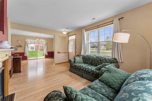 1893 13th St W, Hastings, MN 55033 - living area with a textured ceiling, a fireplace, wood finished floors, baseboards, and an inviting chandelier