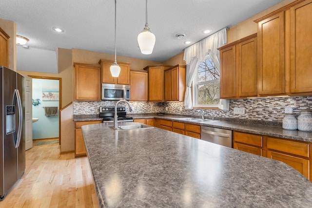 1893 13th St W, Hastings, MN 55033 - kitchen featuring dark countertops, appliances with stainless steel finishes, brown cabinets, and light wood finished floors