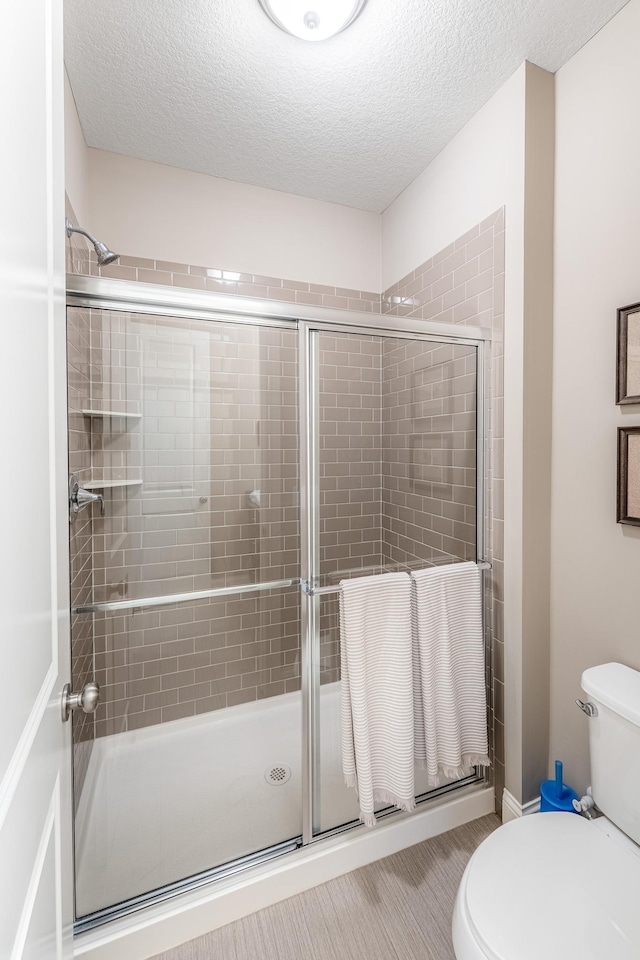 11328 Blazingstar Ln, Lake Elmo, MN 55042 - full bathroom featuring toilet, a shower stall, and a textured ceiling