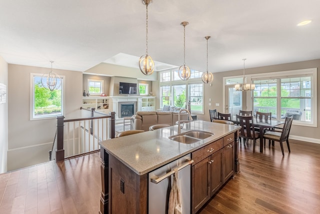 11328 Blazingstar Ln, Lake Elmo, MN 55042 - kitchen with a sink, stainless steel dishwasher, dark wood finished floors, a chandelier, and a fireplace