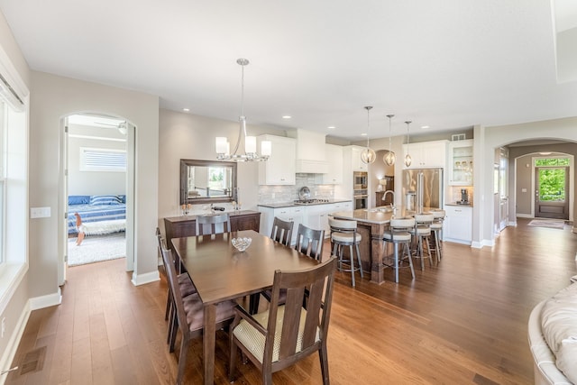 11328 Blazingstar Ln, Lake Elmo, MN 55042 - dining area featuring arched walkways, wood finished floors, baseboards, recessed lighting, and a chandelier