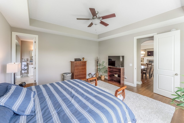11328 Blazingstar Ln, Lake Elmo, MN 55042 - bedroom featuring wood finished floors, arched walkways, a tray ceiling, and baseboards