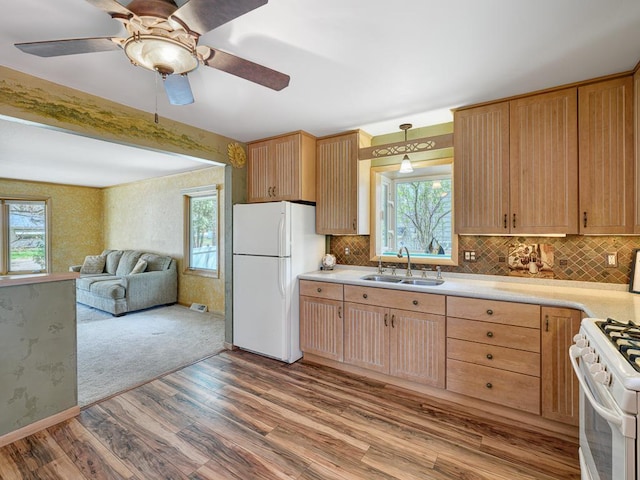 kitchen featuring a sink, white appliances, light wood finished floors, decorative backsplash, and light countertops