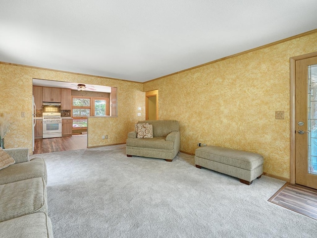 carpeted living room featuring crown molding and wallpapered walls