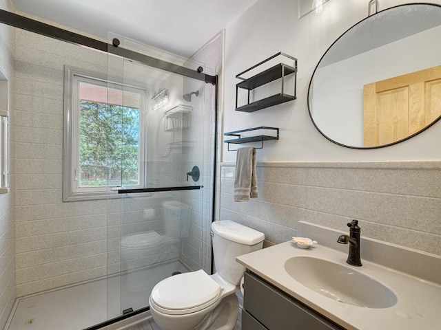 bathroom featuring toilet, vanity, tile walls, and a shower stall