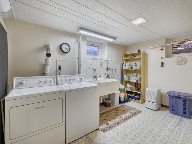 laundry area featuring light floors, laundry area, a textured ceiling, a sink, and separate washer and dryer