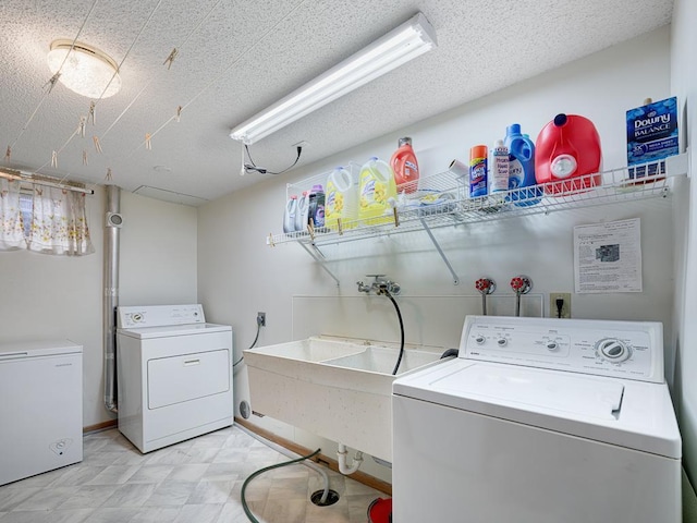 laundry area with a textured ceiling, light floors, a sink, and washer and clothes dryer