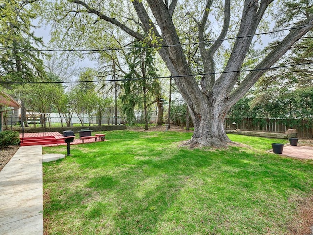 view of property's community featuring a lawn, a deck, and fence