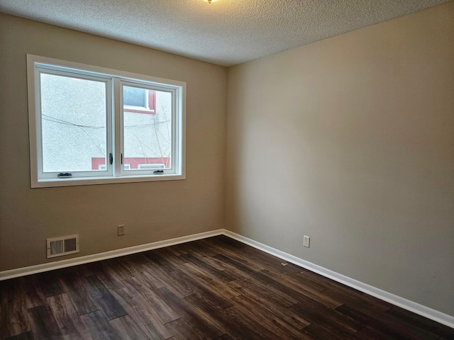 unfurnished room with baseboards, dark wood-type flooring, visible vents, and a textured ceiling