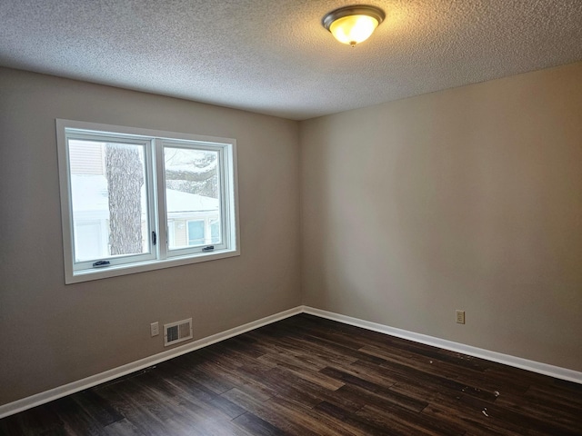 spare room with baseboards, visible vents, a textured ceiling, and dark wood-style flooring