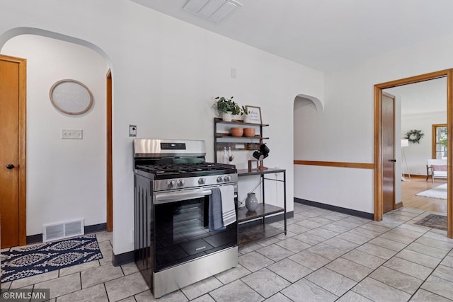 674 Wheelock Pkwy W, Saint Paul, MN 55117 - kitchen with stainless steel gas range, arched walkways, and light tile patterned floors