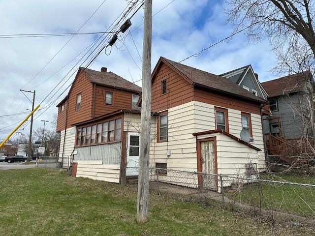 back of property featuring a lawn and fence