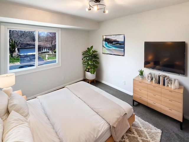 bedroom with dark colored carpet and baseboards