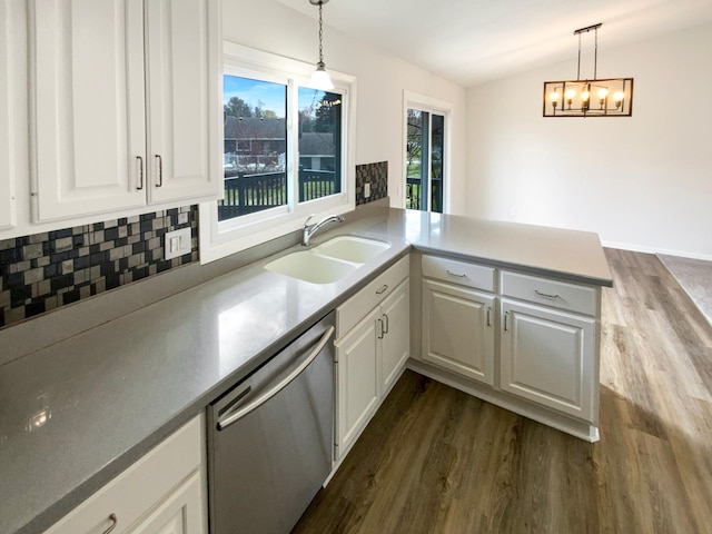 kitchen featuring a peninsula, a sink, backsplash, dishwasher, and dark wood-type flooring