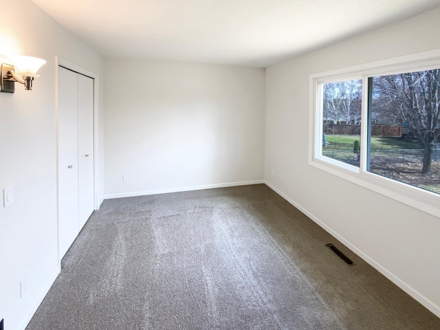 unfurnished bedroom with baseboards, visible vents, carpet, and a closet
