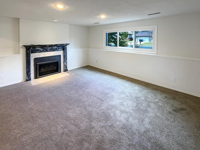 unfurnished living room featuring a fireplace with flush hearth, baseboards, carpet flooring, and recessed lighting