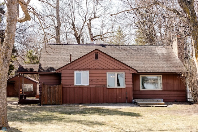 view of front of house with a chimney, a front lawn, and a shingled roof