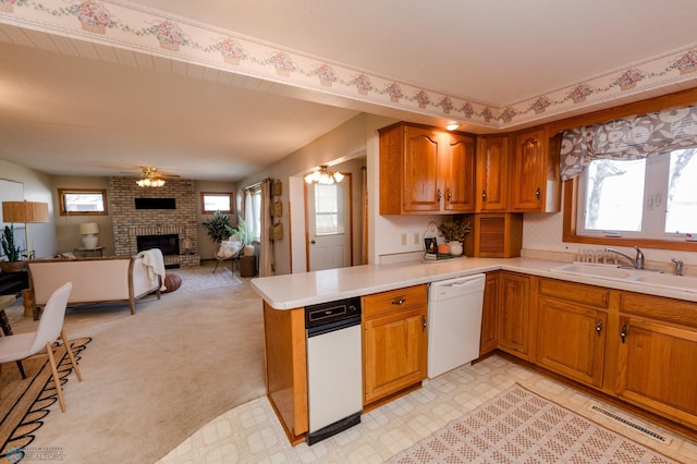 kitchen with brown cabinets, white dishwasher, visible vents, and light countertops