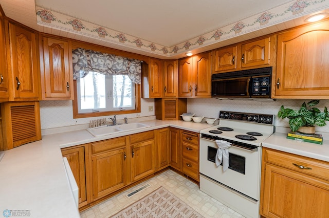 kitchen with white electric stove, a sink, brown cabinetry, black microwave, and light countertops