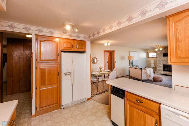 kitchen featuring a ceiling fan, a brick fireplace, white appliances, light floors, and light countertops