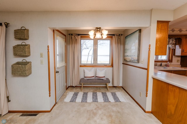 interior space with visible vents, light carpet, baseboards, and an inviting chandelier