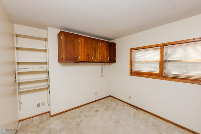 unfurnished room featuring baseboards, visible vents, and light colored carpet