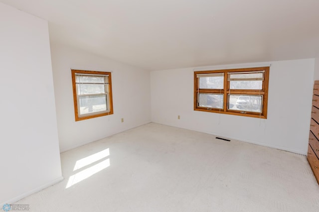 spare room with lofted ceiling, visible vents, and light carpet