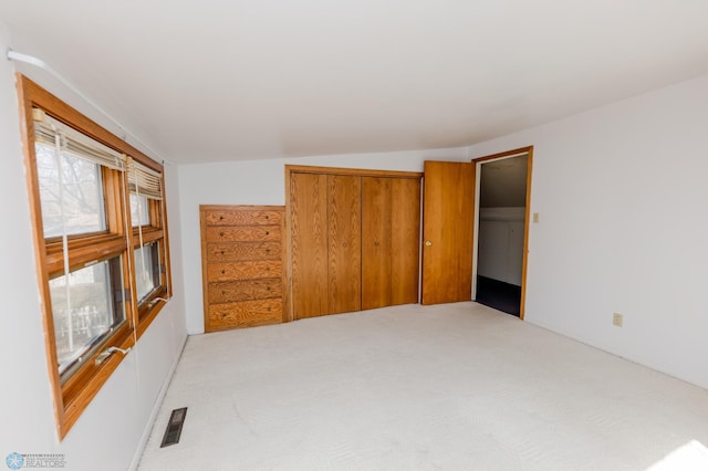 unfurnished bedroom featuring a closet, visible vents, and light carpet
