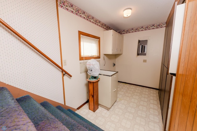 clothes washing area with light floors, baseboards, cabinet space, and electric panel