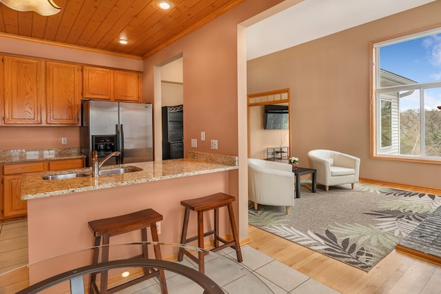kitchen with light stone countertops, recessed lighting, a sink, wood ceiling, and stainless steel fridge with ice dispenser