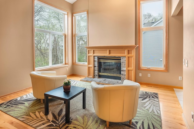 living area featuring baseboards, a glass covered fireplace, and wood finished floors