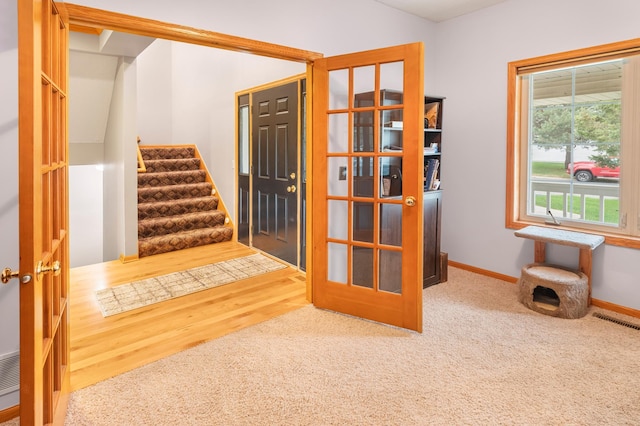 interior space with wood finished floors, visible vents, stairway, carpet flooring, and baseboards