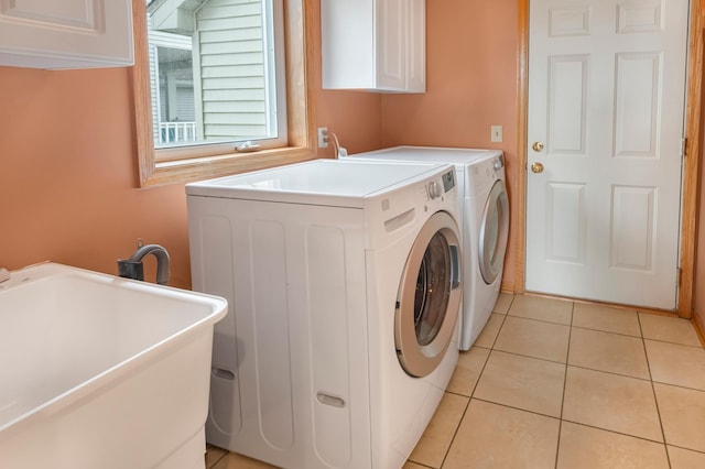 laundry room featuring cabinet space, washing machine and clothes dryer, light tile patterned flooring, and a sink
