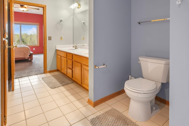 ensuite bathroom featuring a sink, toilet, tile patterned flooring, a ceiling fan, and baseboards
