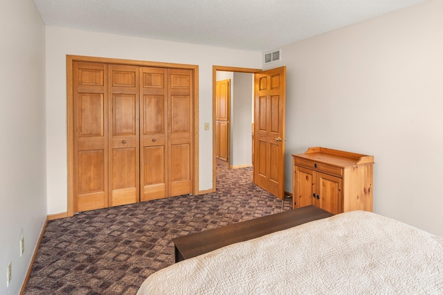 bedroom featuring a closet, baseboards, visible vents, and dark carpet
