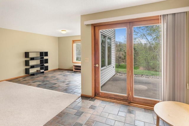 doorway with baseboards and stone tile floors