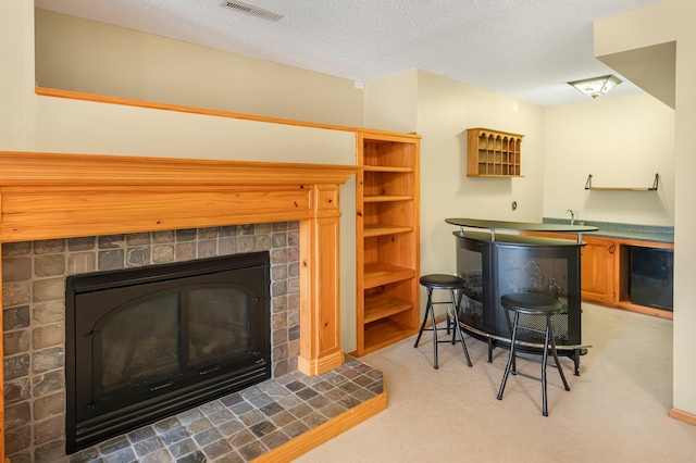 bar featuring a textured ceiling, a fireplace, visible vents, and light colored carpet
