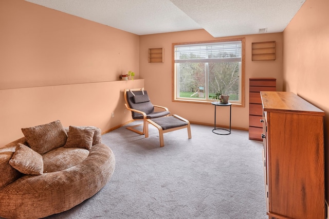 living area with a textured ceiling, baseboards, visible vents, and carpet