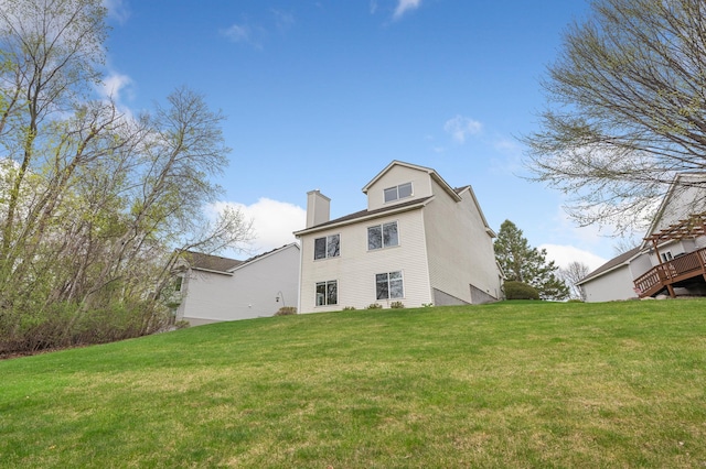 back of property with a chimney and a lawn